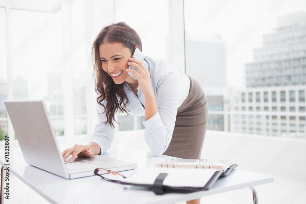 Happy businesswoman using laptop at her desk Happy businesswoman using laptop at her desk