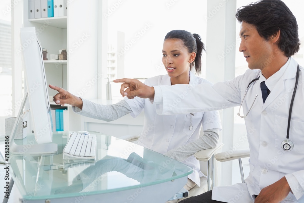 Two doctors pointing to computer screen Two doctors pointing to computer screen