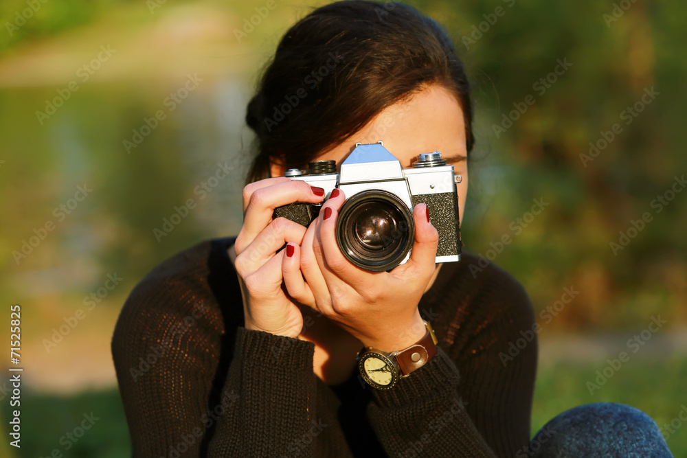 Young woman taking a picture with an old camera