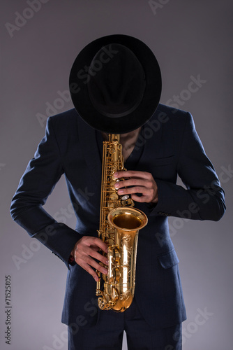 Fotografie Portrait of a jazz man in a suit with a hat hiding his face and
