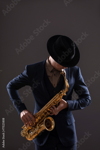 Canvas Print Portrait of a jazz man in a suit with a hat hiding his face and