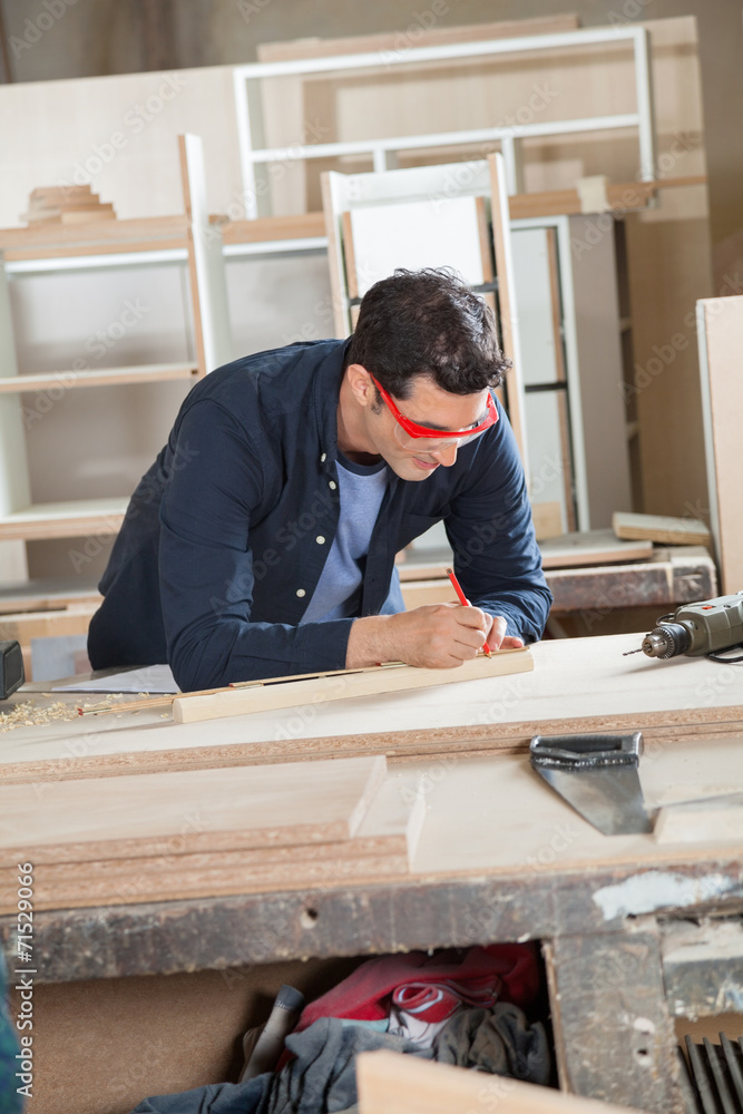 Carpenter Measuring Wood At Workbench Carpenter Measuring Wood At Workbench