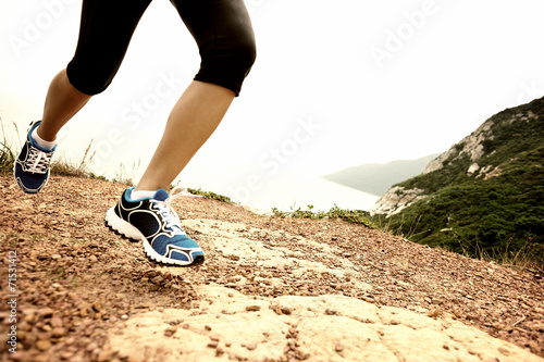 young woman legs running on seaside mountain trail 