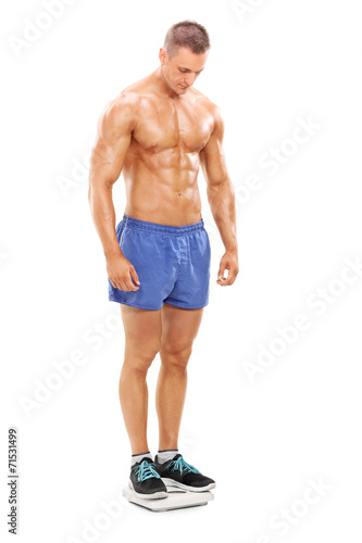 Handsome shirtless man standing on a weight scale
