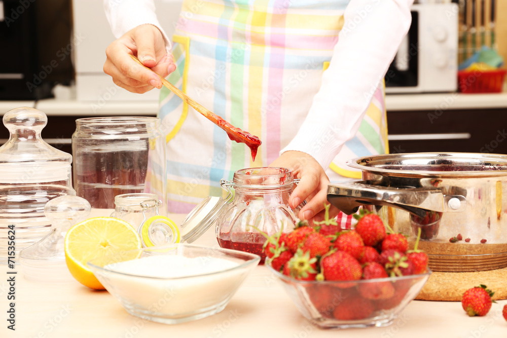 Woman cooking strawberry jam in kitchen Woman cooking strawberry jam in kitchen