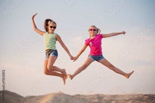 two girls jumping over blue sky