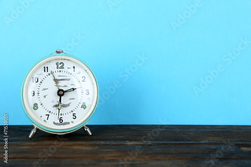 Wallpaper Mural Old alarm clock on wooden table on blue background Torontodigital.ca