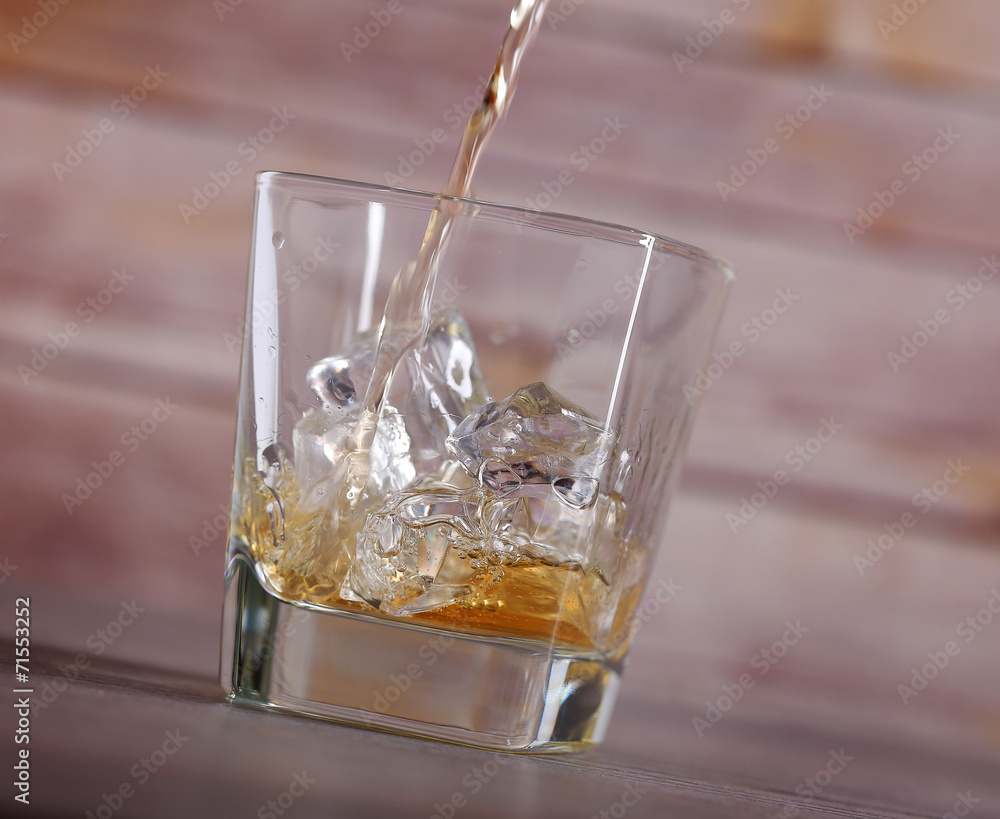 Pouring brandy into glass with ice Pouring brandy into glass with ice
