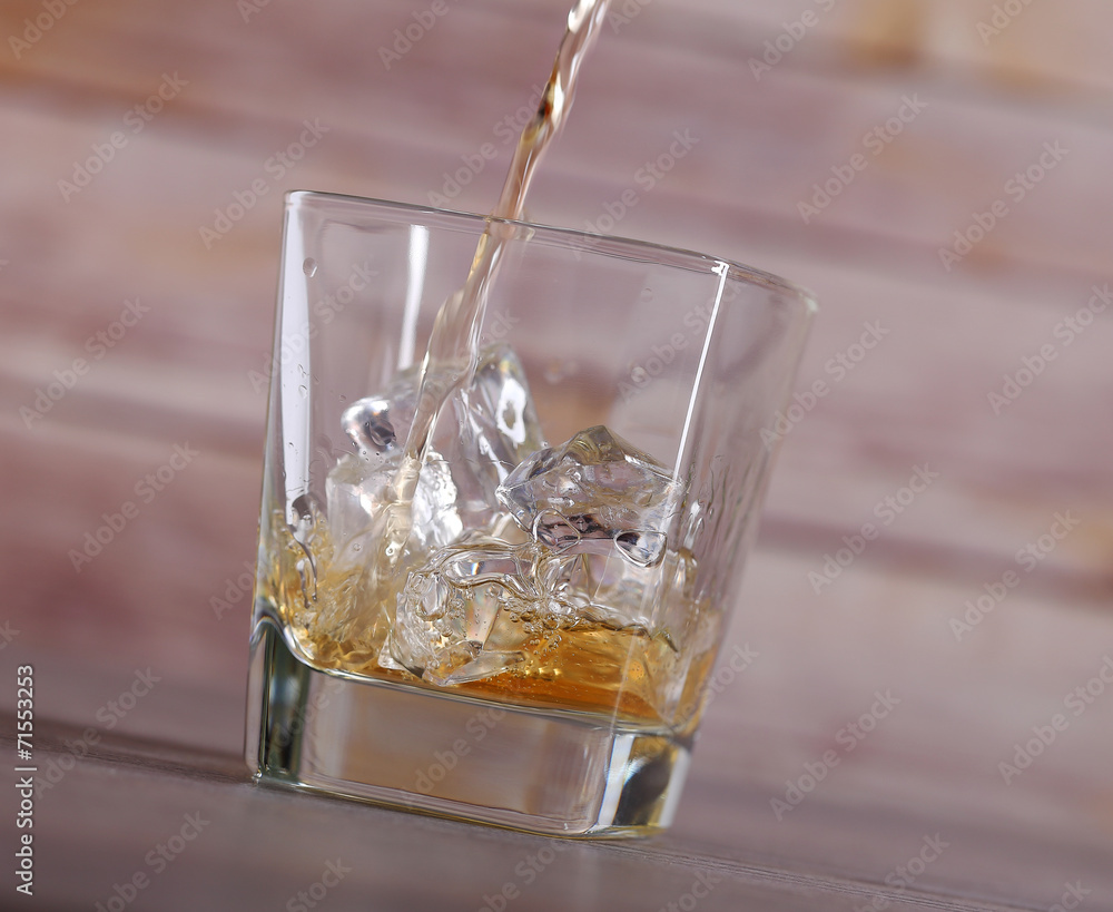 Pouring brandy into glass with ice Pouring brandy into glass with ice