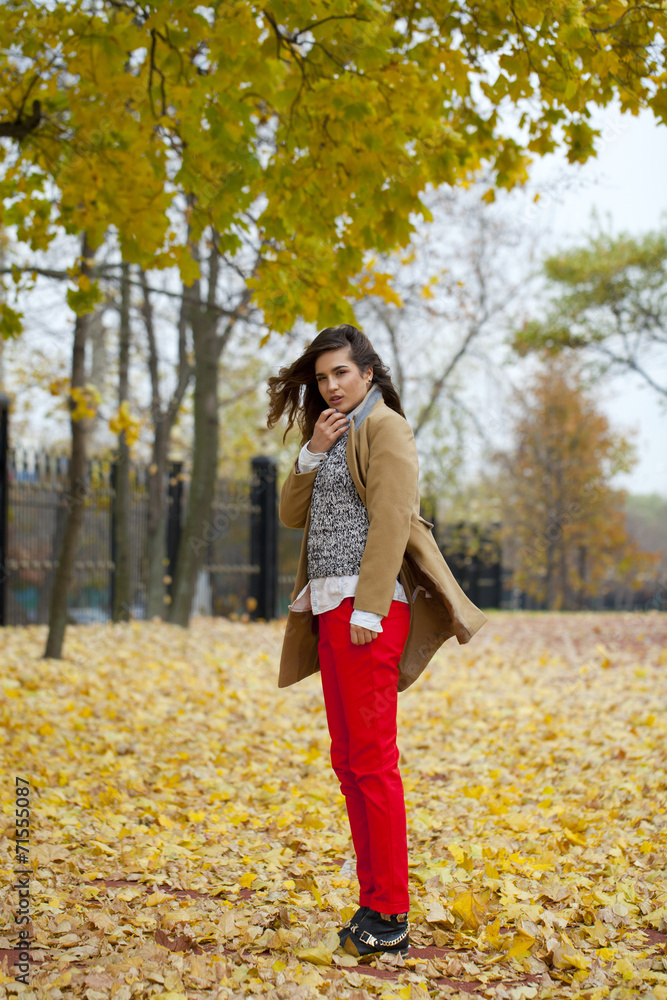 Young woman in fashion coat walking in autumn park Young woman in fashion coat walking in autumn park