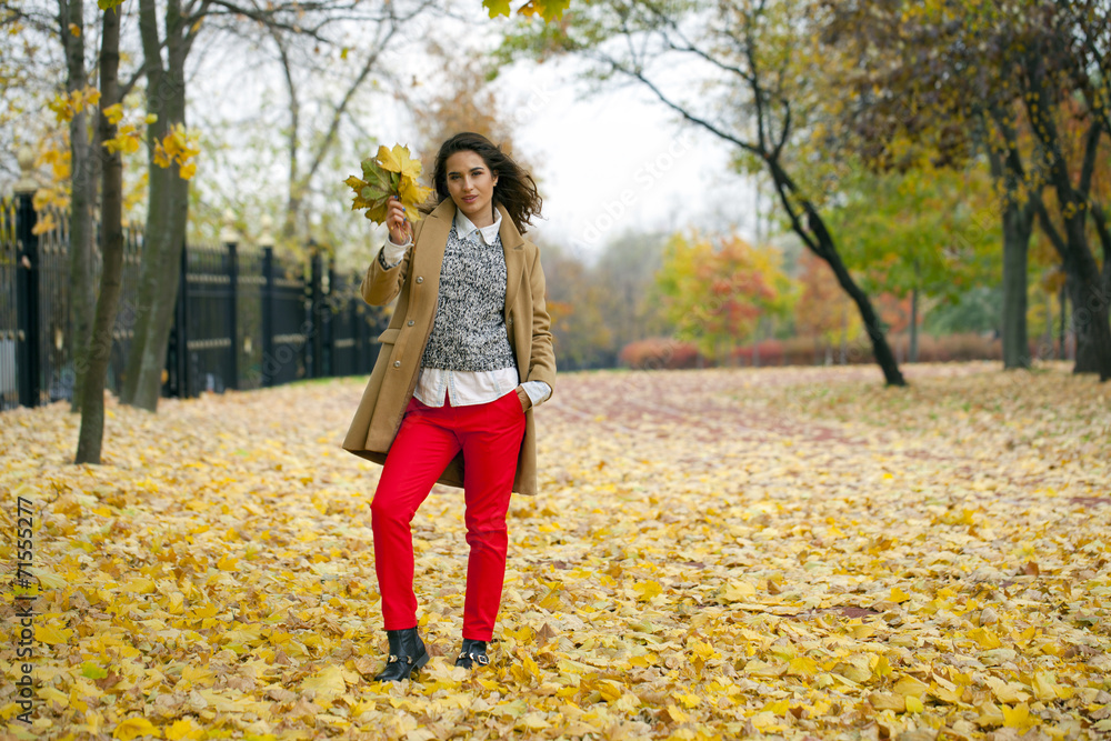Young woman in fashion coat walking in autumn park