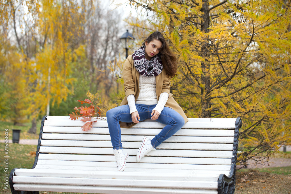 Beautiful woman sitting on a bench in autumn park Beautiful woman sitting on a bench in autumn park