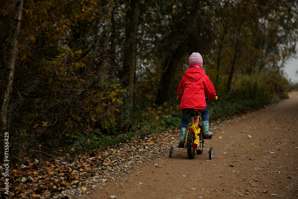 Obraz premium Small child on bike rides on the road