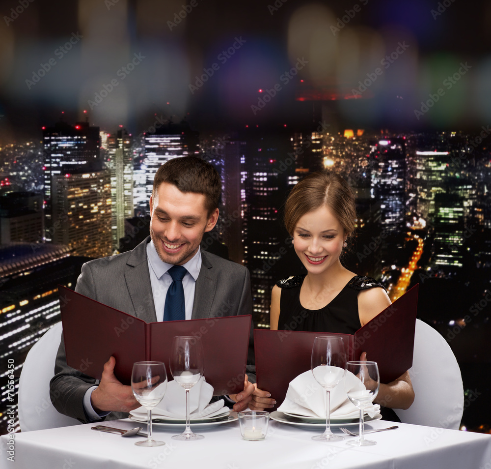 smiling couple with menus at restaurant