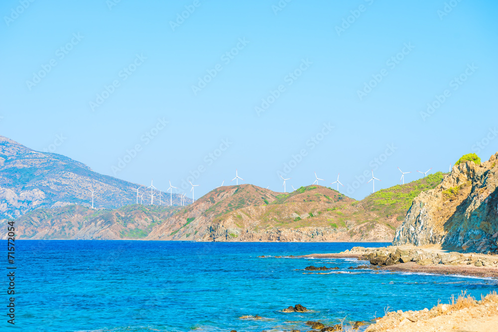 windmills generate electricity in the mountains near the sea