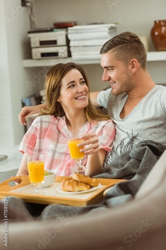 Cute couple relaxing on couch with breakfast