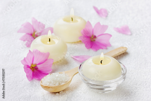 spa composition with sea salt in spoon, flowers and candles