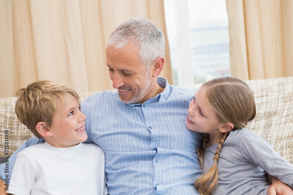 Father smiling with his children on sofa Father smiling with his children on sofa