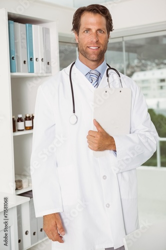 Confident doctor with reports at medical office