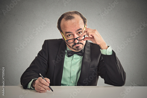man with glasses skeptically looking at you sitting at desk