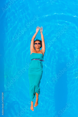 Beautiful young girl floating in pool on her back