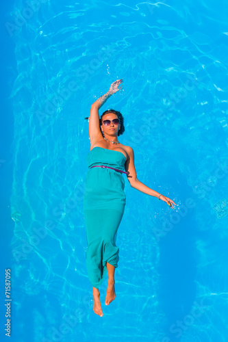 Beautiful young girl floating in pool on her back