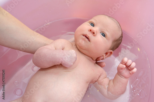 Bathing of the baby in a pink tray