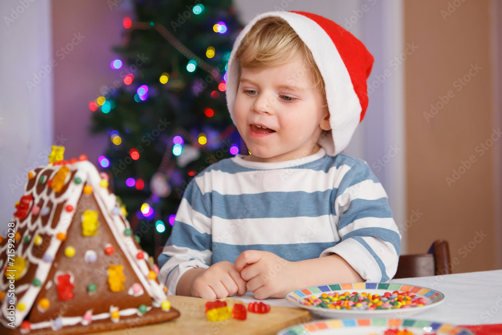 Little toddler boy happy about gingerbread cookie house
