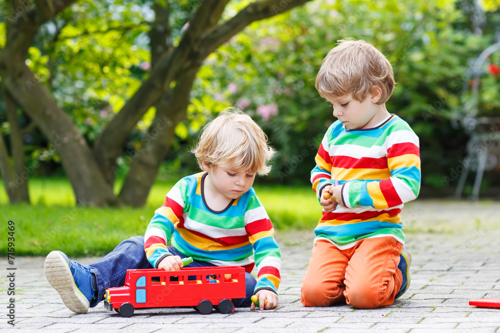 Two little friends playing with red school bus Two little friends playing with red school bus