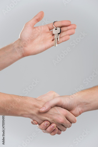 Two businessperson shaking hands on grey background.
