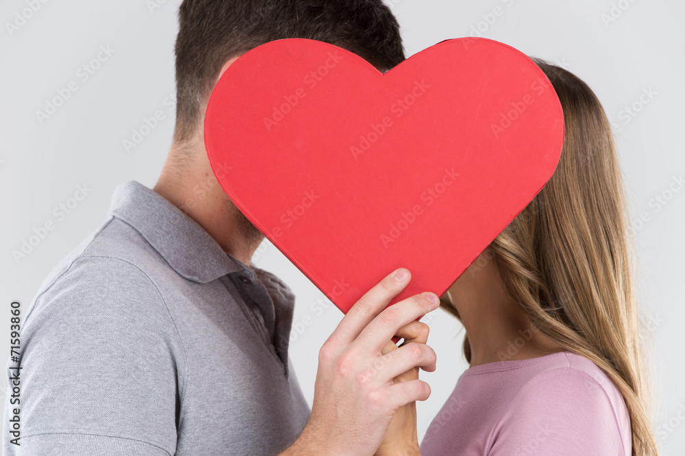 Two young dates behind heart with their faces close Two young dates behind heart with their faces close