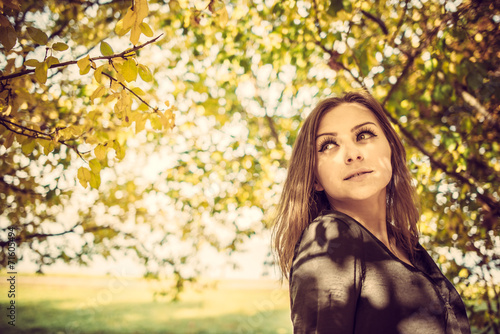 Young pretty elegant lady posing near colourfull tree at autumn