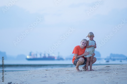 Mother and daughter on beach and cargo ship on back anchored in