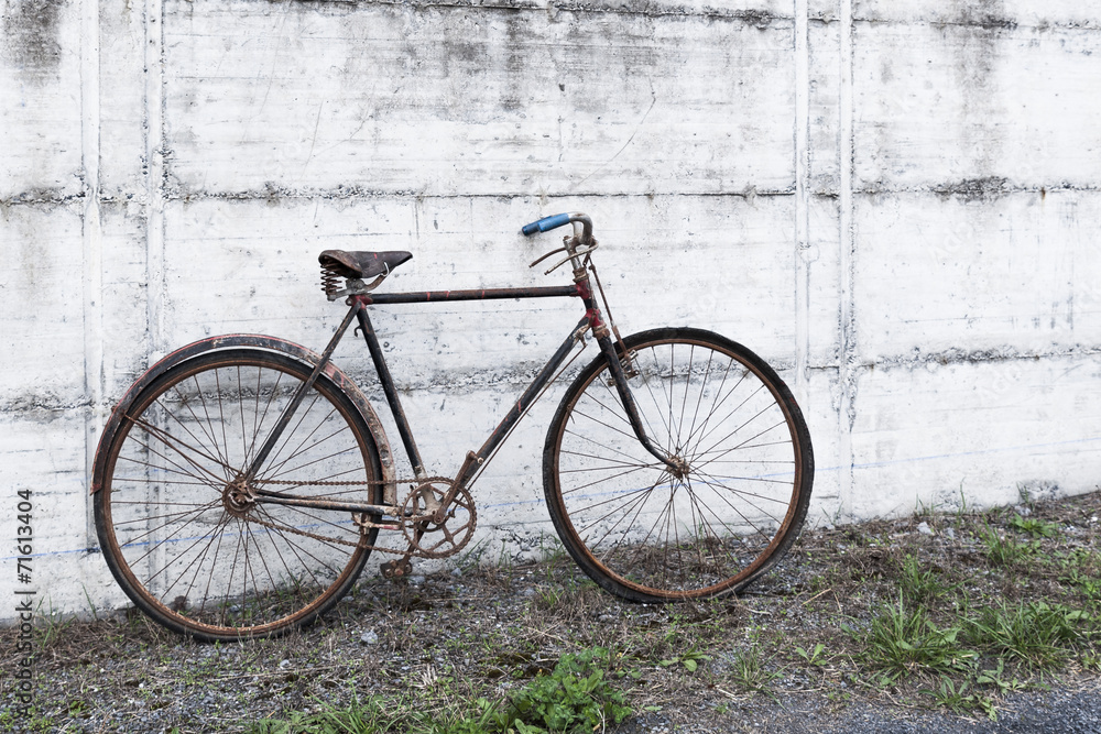 Antique or retro oxidized bicycle outside on a concrete wall