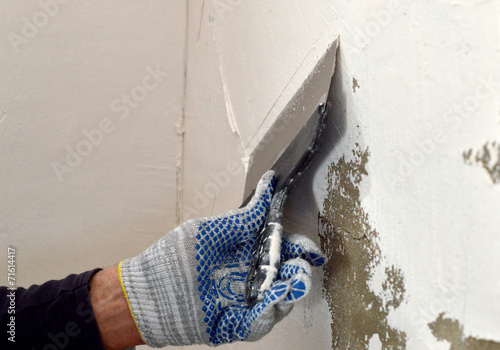 The process of applying a white putty on concrete gray wall