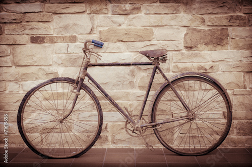 Antique or retro oxidized bicycle outside on a stone wall © irantzuarb