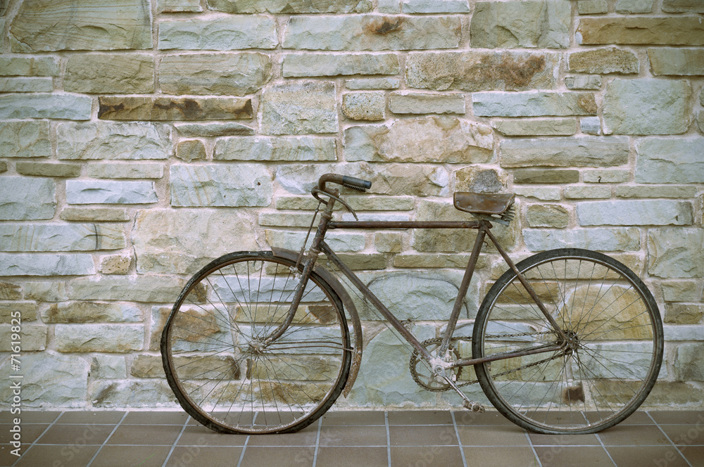 Antique or retro oxidized bicycle outside on a stone wall