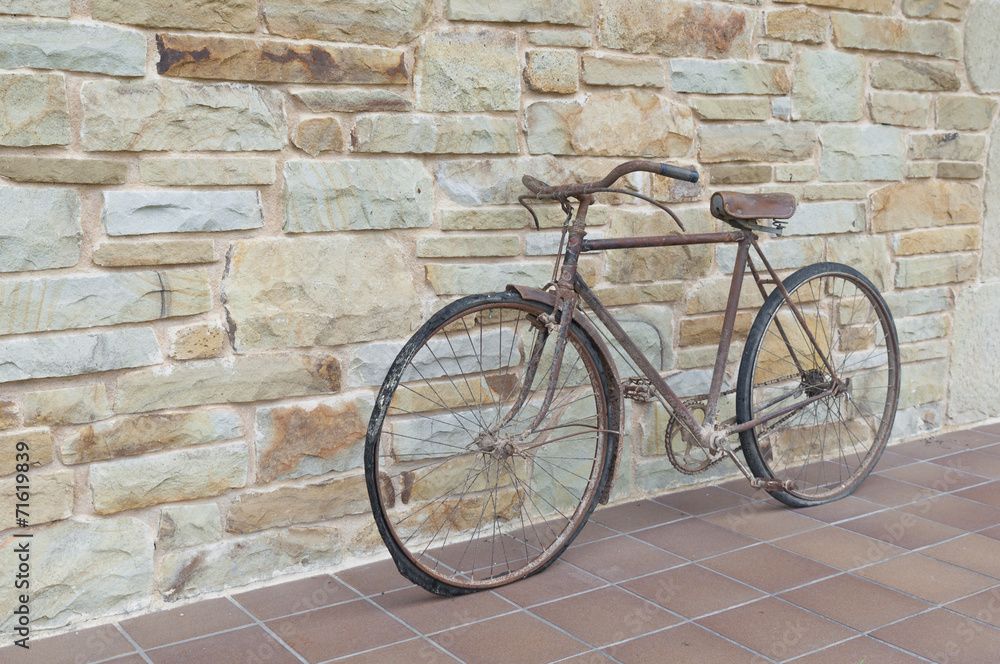 Antique or retro oxidized bicycle outside on a stone wall
