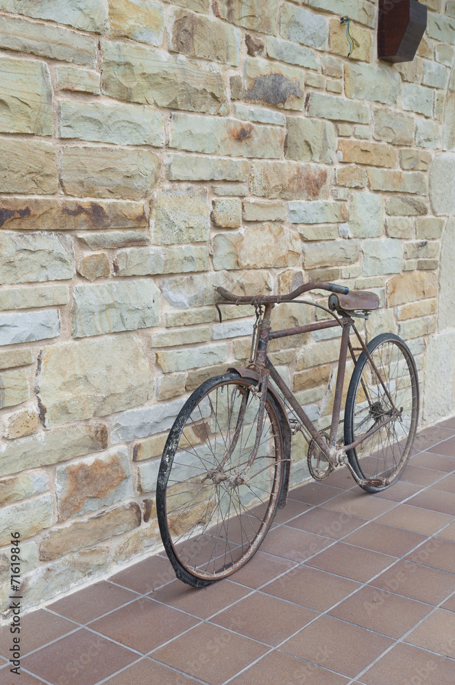 Antique or retro oxidized bicycle outside on a stone wall