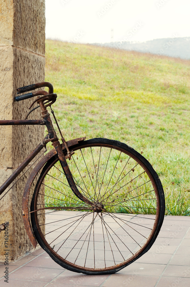 Fototapeta premium Antique or retro oxidized bicycle outside on a stone wall