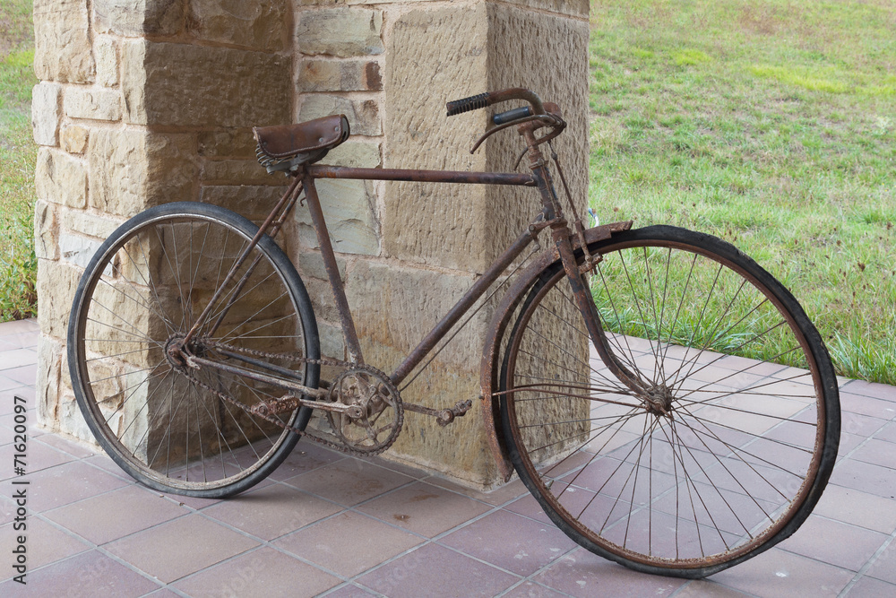 Antique or retro oxidized bicycle outside on a stone wall