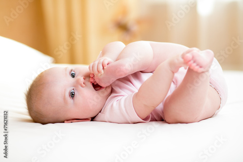 baby girl lying and pulling her legs to her mouth