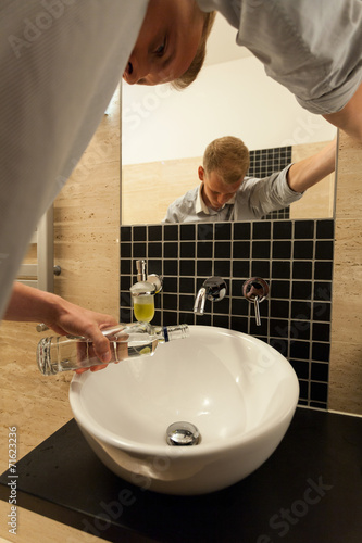 Obraz na płótnie Man poured a bottle of vodka down the sink