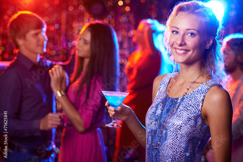 Beautiful girl posing with cocktail in nightclub