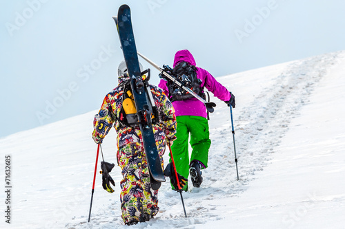 Two skiers rise walk uphill