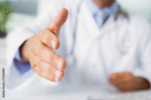 Mid section of doctor offering handshake