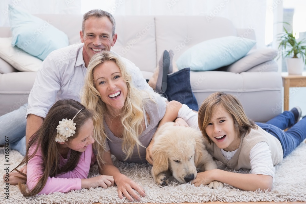 Laughting family with their pet yellow labrador on the rug
