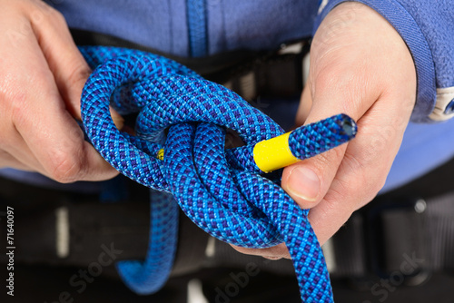 Female hands holding a climbing rope making a secure node