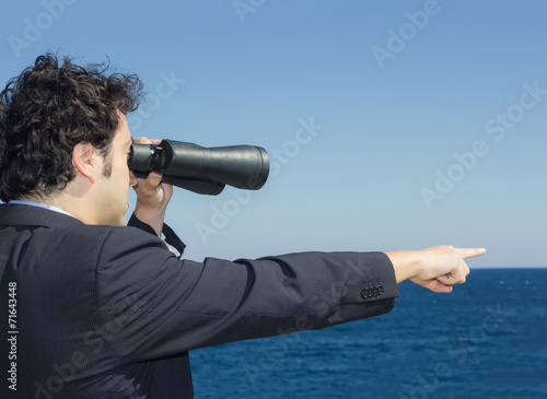 businessman looking at the horizon with binoculars photo