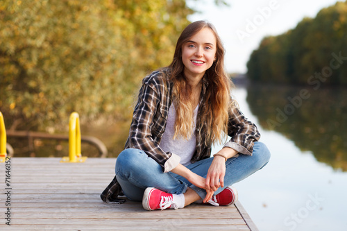 Young beautiful girl sitting on a pier
